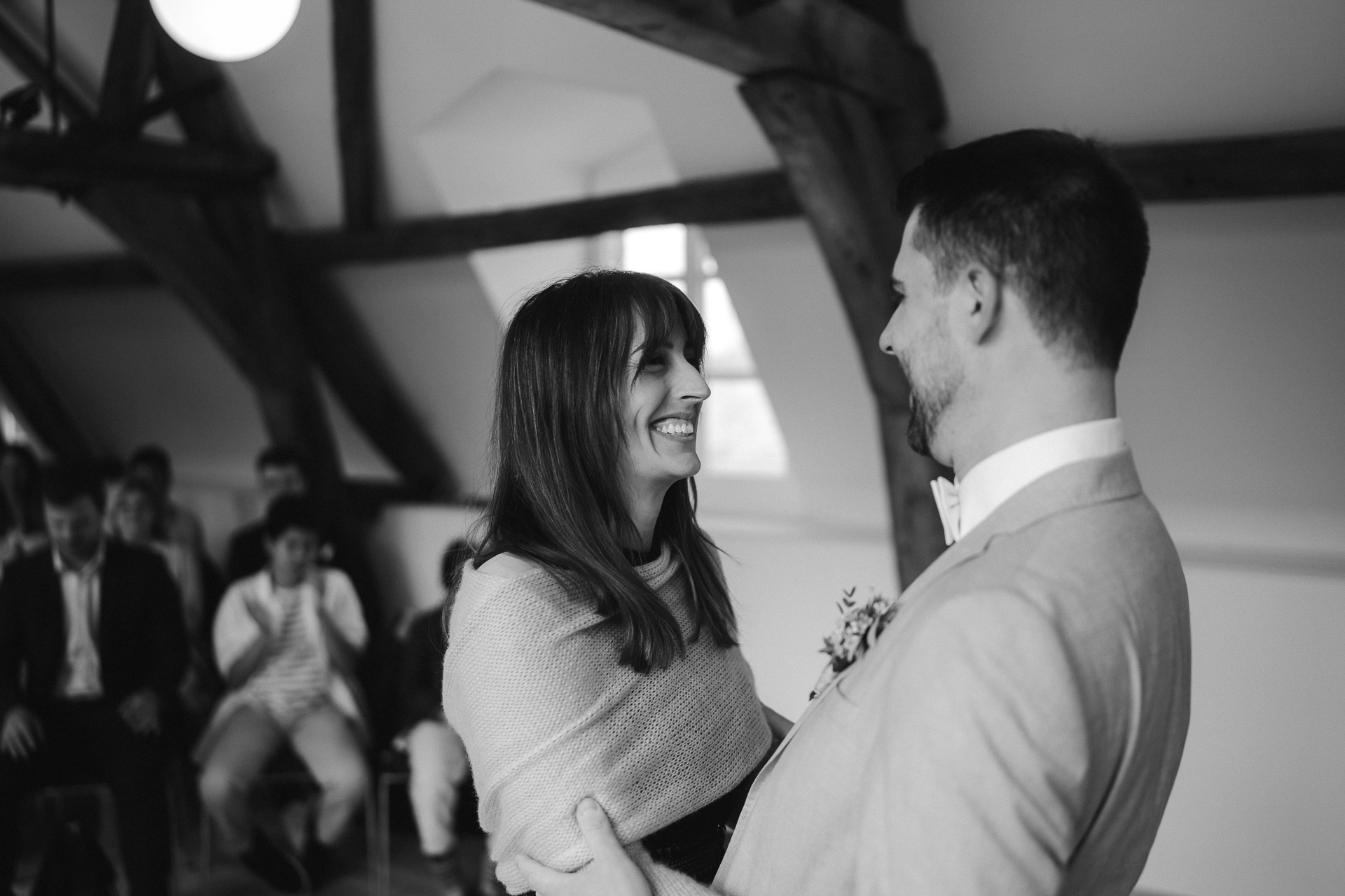 Trauzeugin gratuliert dem Bräutigam zur Hochzeit und lächelt diesen an, im Hintergrund die Gäste applaudieren - Hochzeitsfotografie Standesamt Heinsberg