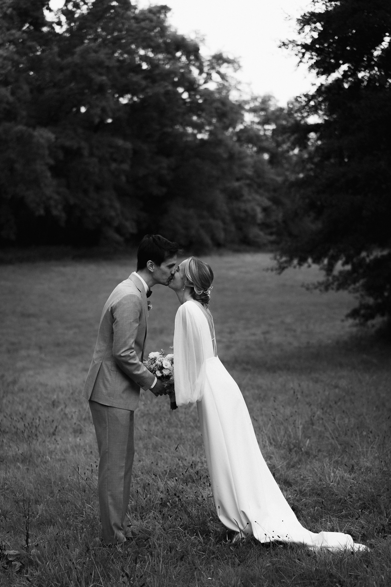 Brautpaar küsst sich auf einer Wiese. Braut trägt ein langes weißes Brautkleid - Fotograf Hochzeit Erkelenz