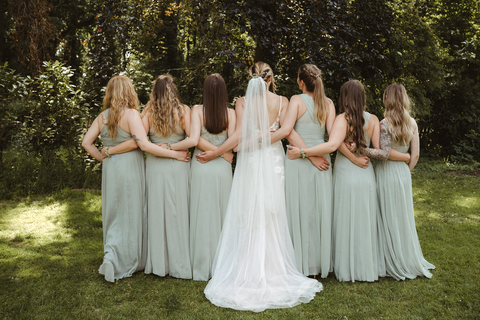 Wunderschönes Gruppenfoto der Braut mit ihren Brautjungfern im Grünen - natürliche Hochzeitsfotografie
