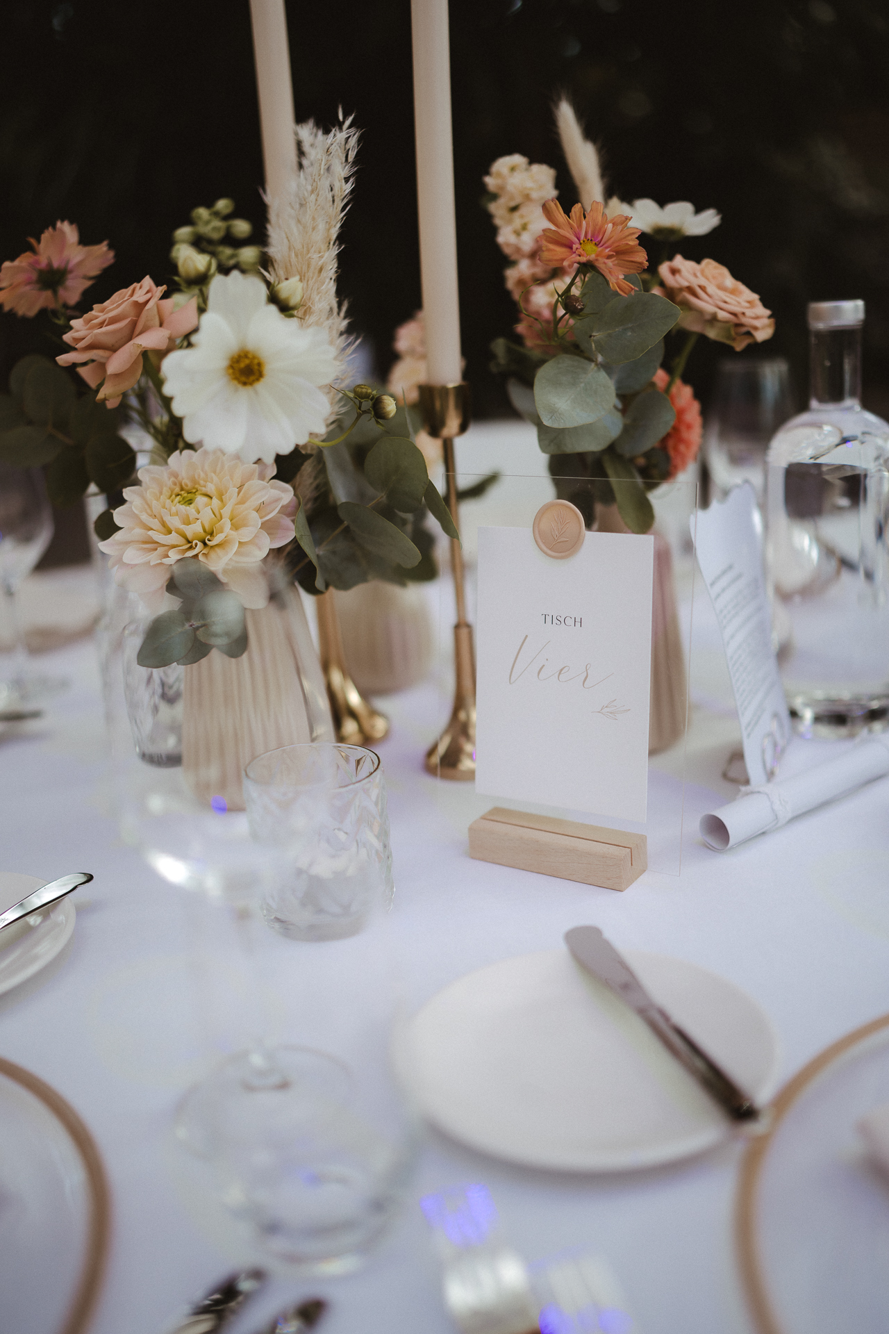 Foto von einer Tischkarte auf einem Hochzeitstisch, der gedeckt ist mit schönen Tellern, Besteck, und blühenden Blumen - Aachener Hochzeitsfotograf vondergraphy
