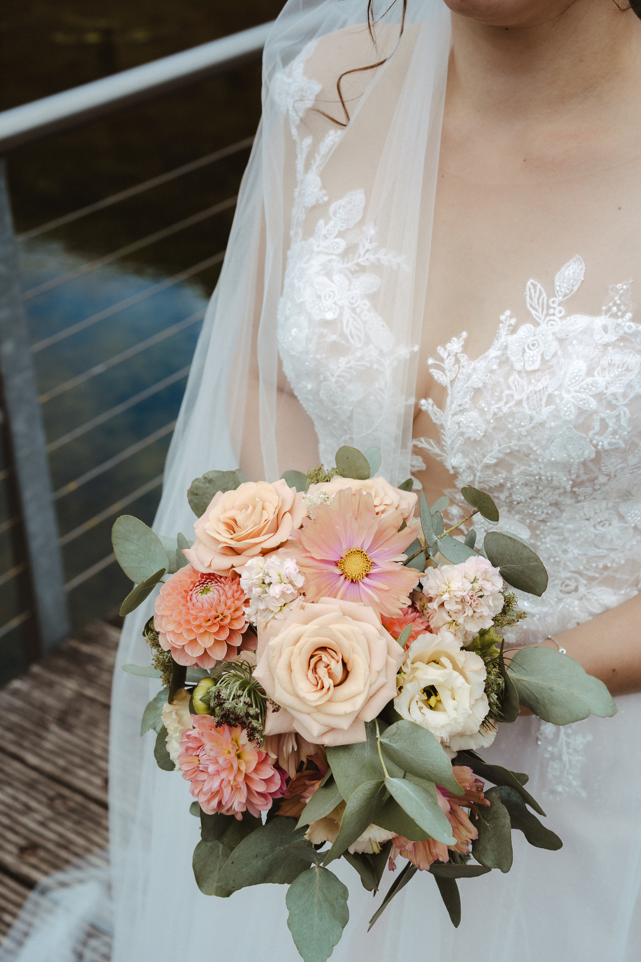 Detailaufnahme von einer Braut mit Schleier, Brautkleid mit Spitze und Brautstrauß - eine Locke fällt sanft auf Ihre Schulter - Hochzeitsfotos aus Erkelenz
