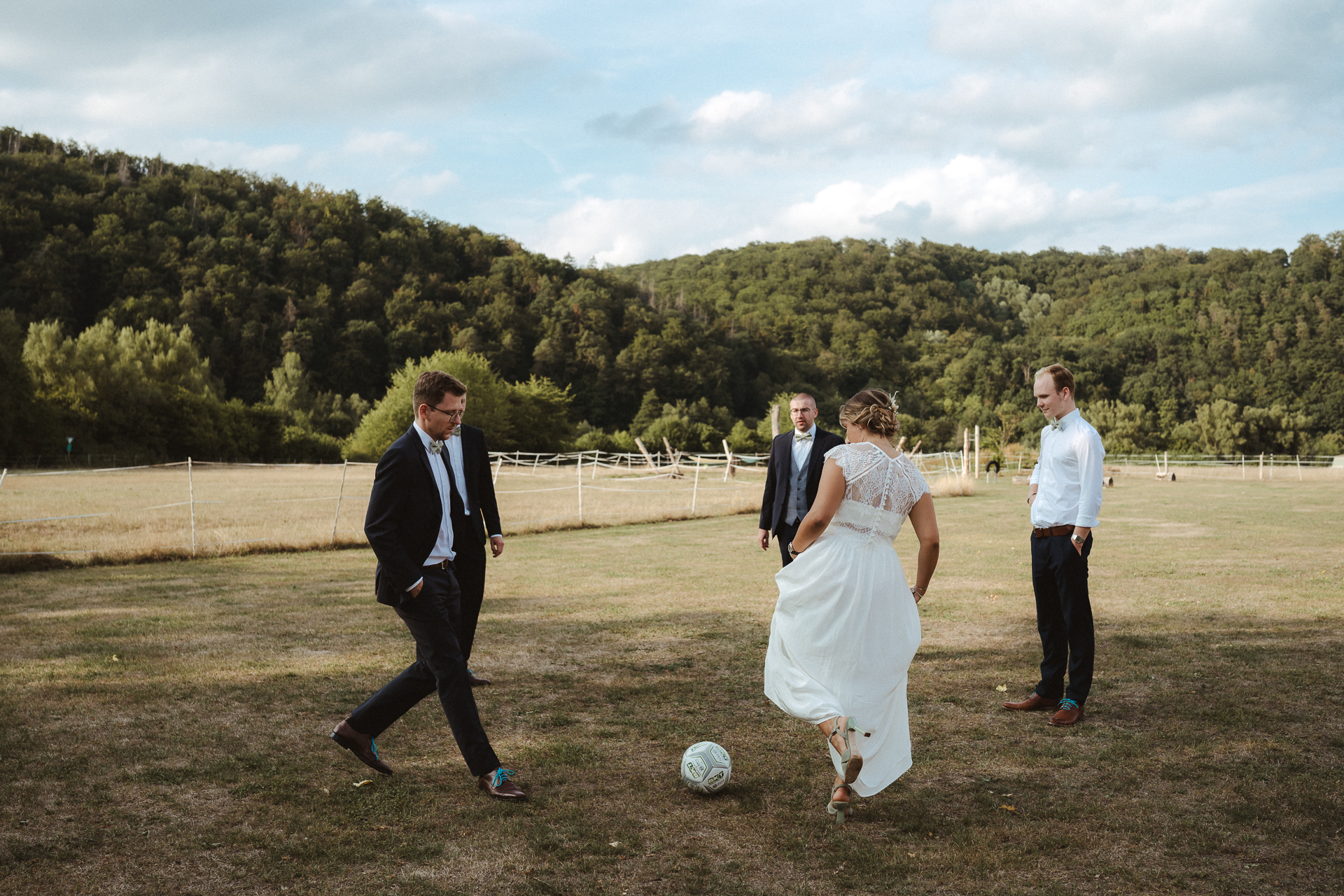 Braut spielt Fußball auf einer grünen Wiese mit ihren Gästen - natürliche Hochzeitsfotos Erkelenz