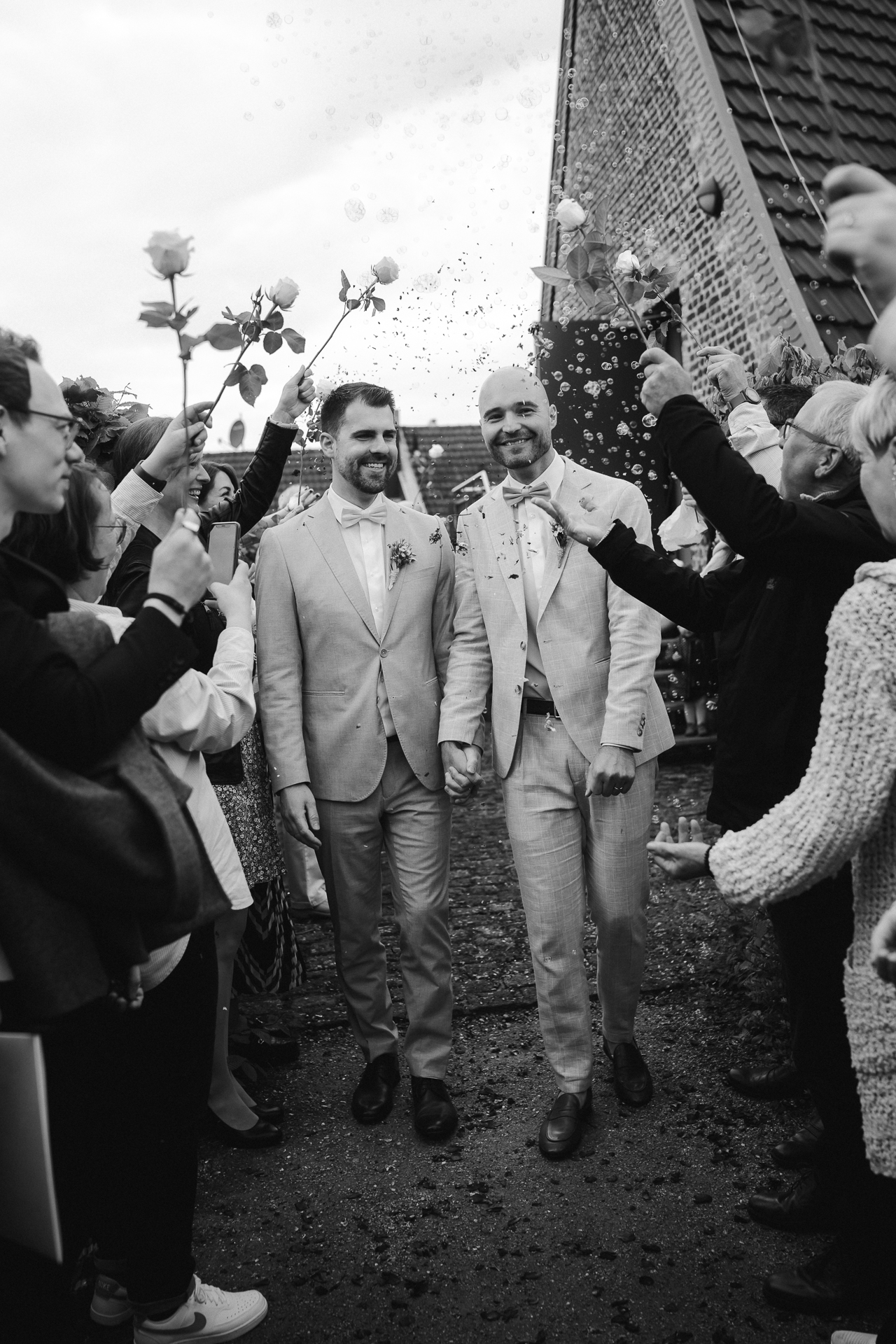 Brautpaar läuft durch einen Tunnel aus weißen Rosen und Seifenblasen - emotionale, authentische Hochzeitsfotografie Heinsberg