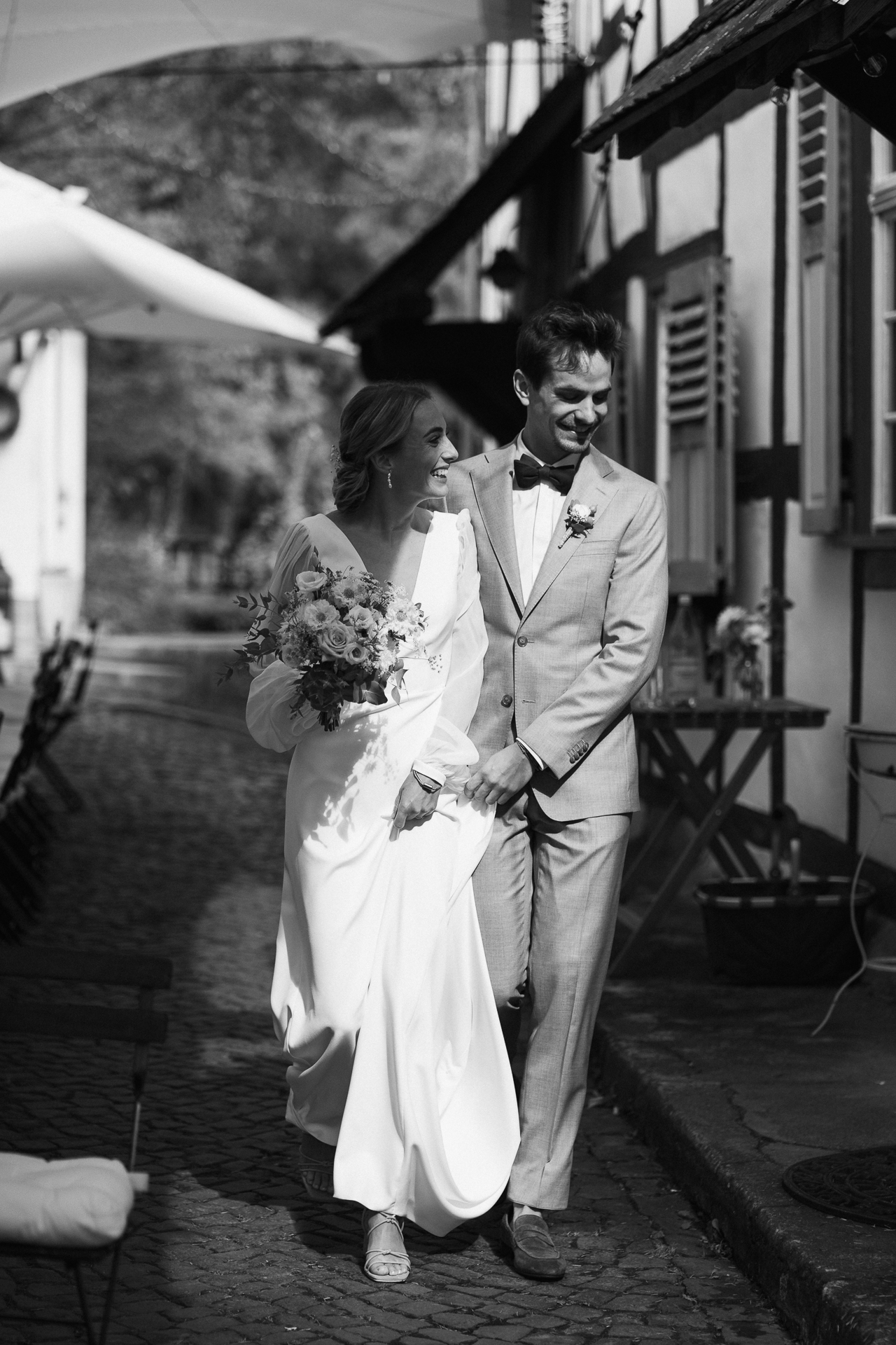 Brautpaar läuft durch den Innenhof einer historischen Location und wird von Sonnenlicht angestrahlt - Hochzeitsreportage Aachen