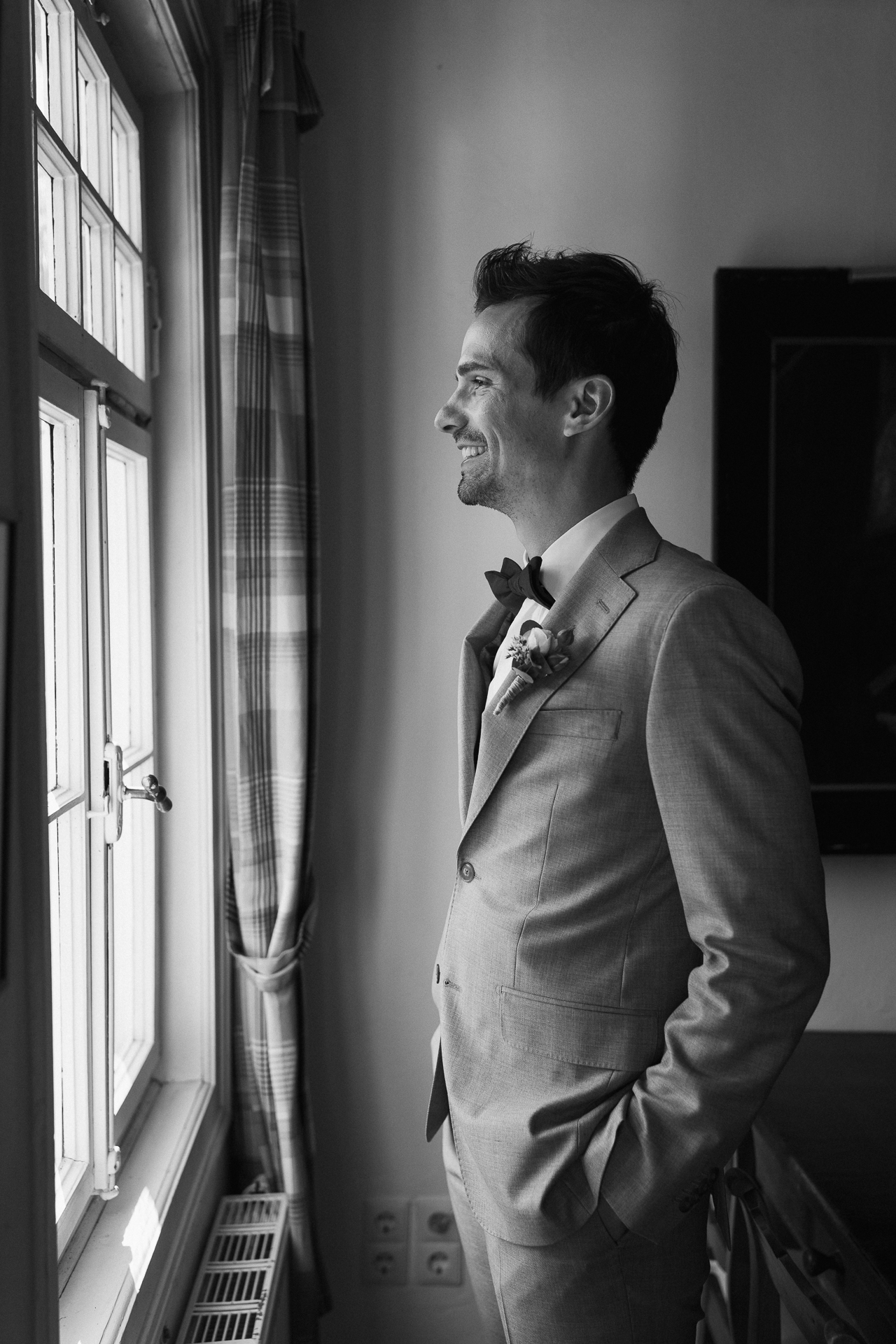 Getting Ready Foto vom Bräutigam, wie dieser aus dem Fenster schaut - emotionale Reportage Hochzeit