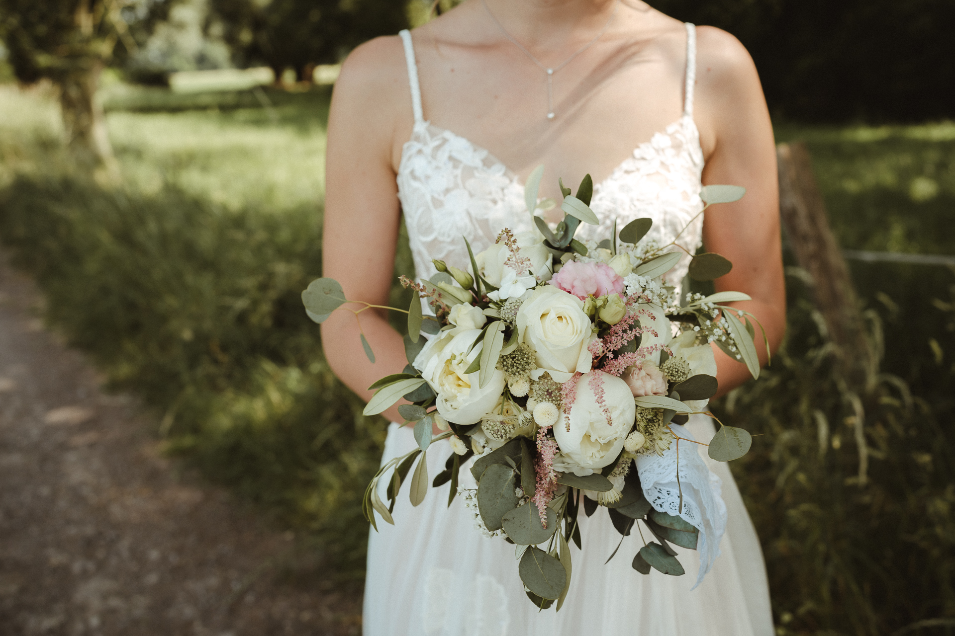 Detailfoto vom Blumenstrauß und Spitzenkleid der Braut im Grünen - Hochzeitsfotografie Erkelenz