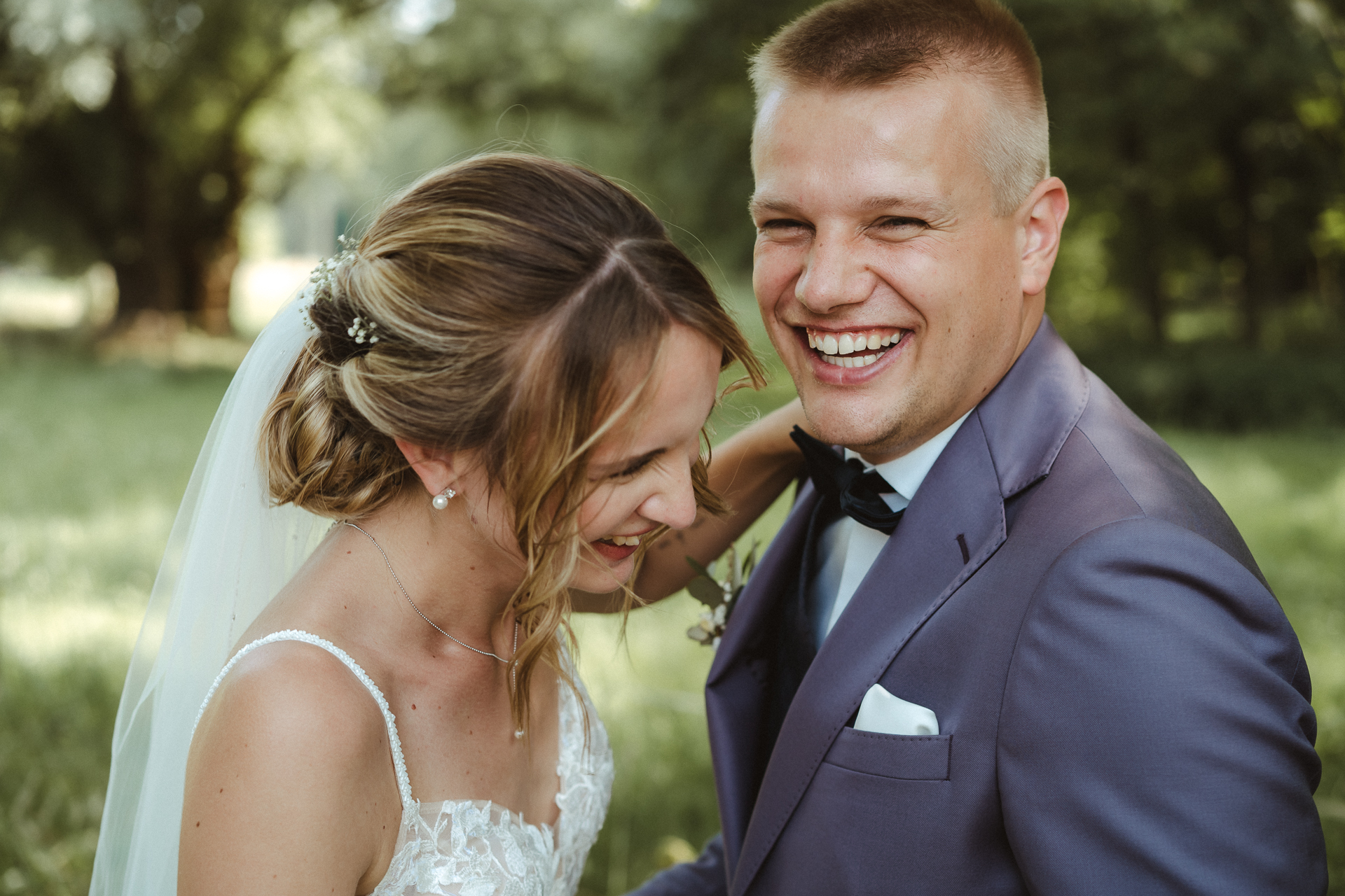 Foto von einem lachenden Brautpaar auf einer grünen Wiese - Hochzeitsfotograf für natürliche Bilder in Erkelenz