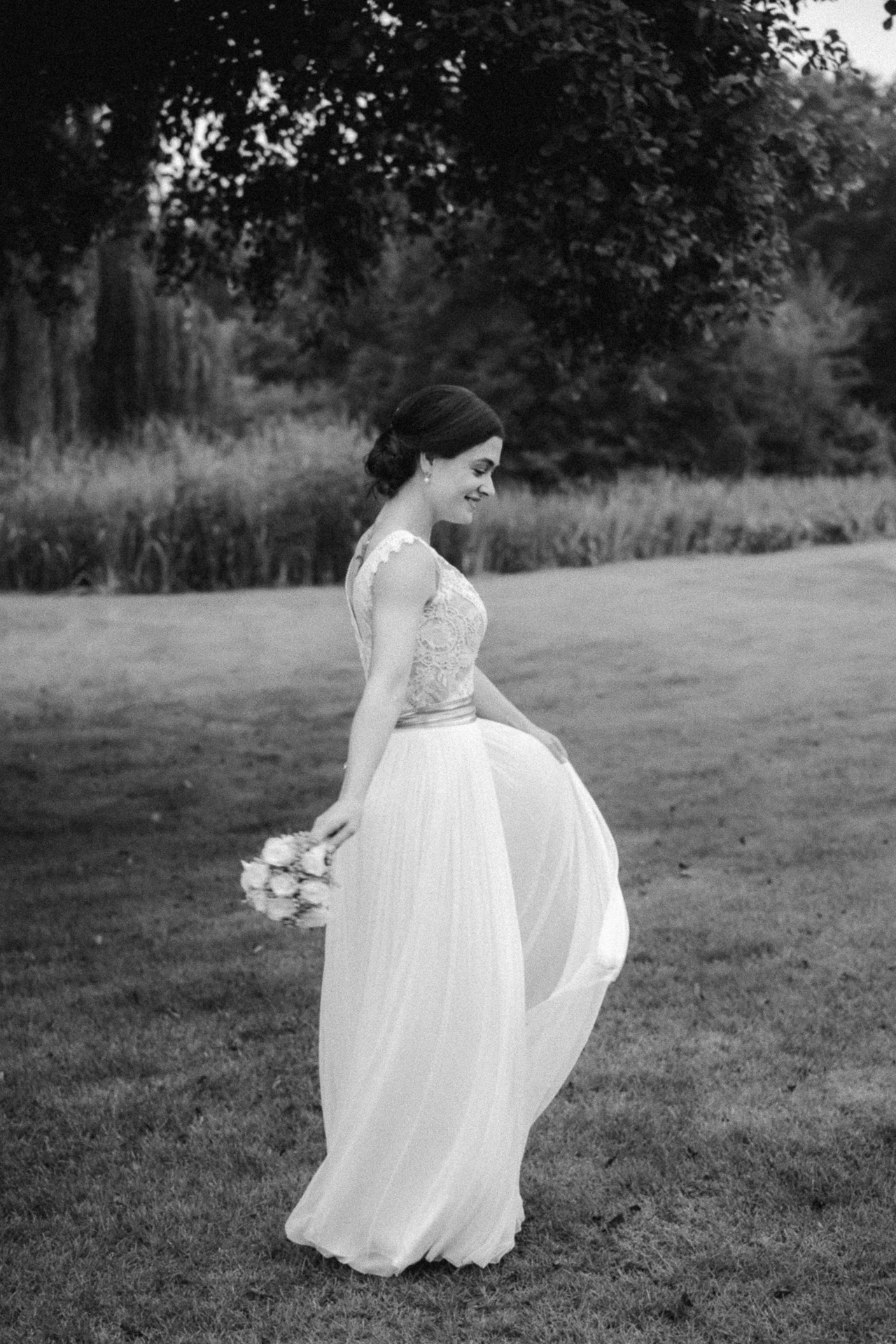 Hochzeitsportraits - wunderschöne Braut tänzelt mit ihrem Brautkleid über eine Wiese