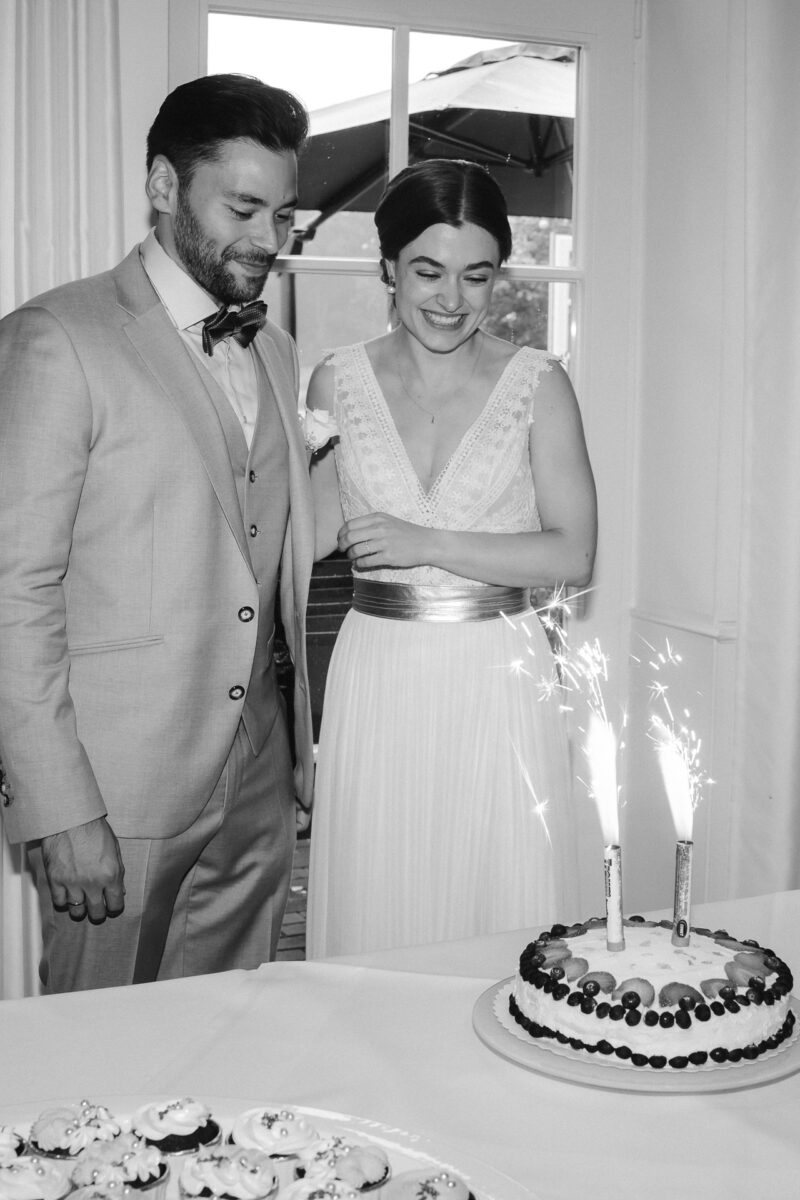 Brautpaar steht vor ihrer Hochzeitstorte und das Tischfeuerwerk brennt - Emotionale Trauung in Erkelenz