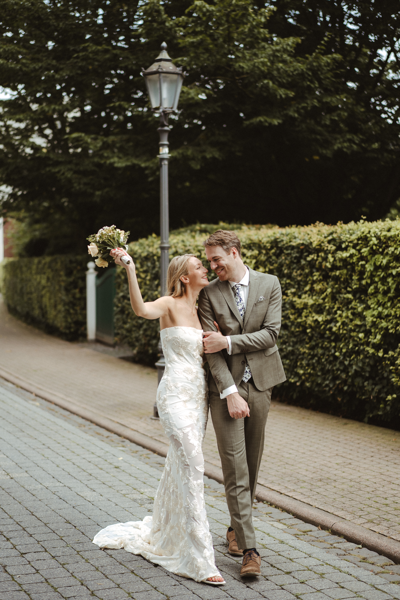Brautpaar lacht sich an und schlendert über die Straße am Standesamt Erkelenz - Hochzeitsreportage Erkelenz