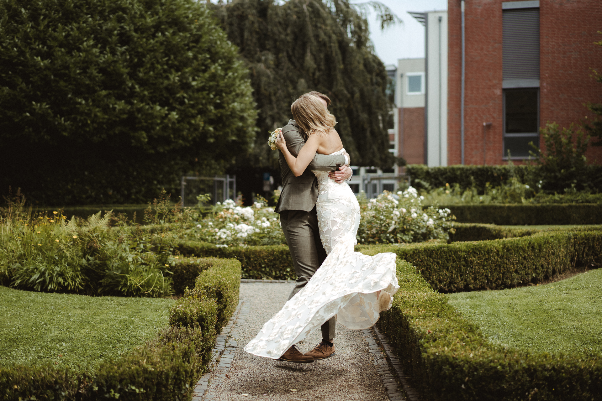Braut wird von Ihrem Bräutigam getragen und in der Luft gedreht im Park des Standesamt Erkelenz - emotionale Hochzeitsfotos