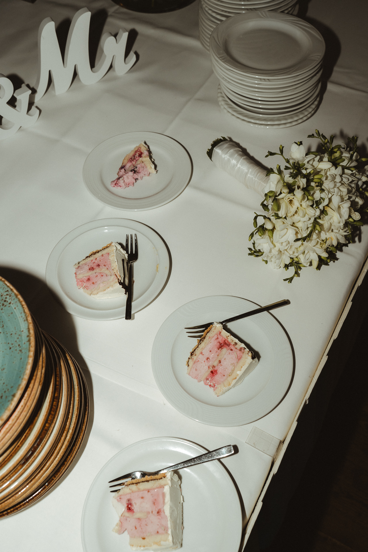 Angeschnittene Hochzeitstore liegt auf vier Tellern , daneben liegt der Brautstrauß - Blitzfotografie aus Erkelenz auf einer Hochzeit