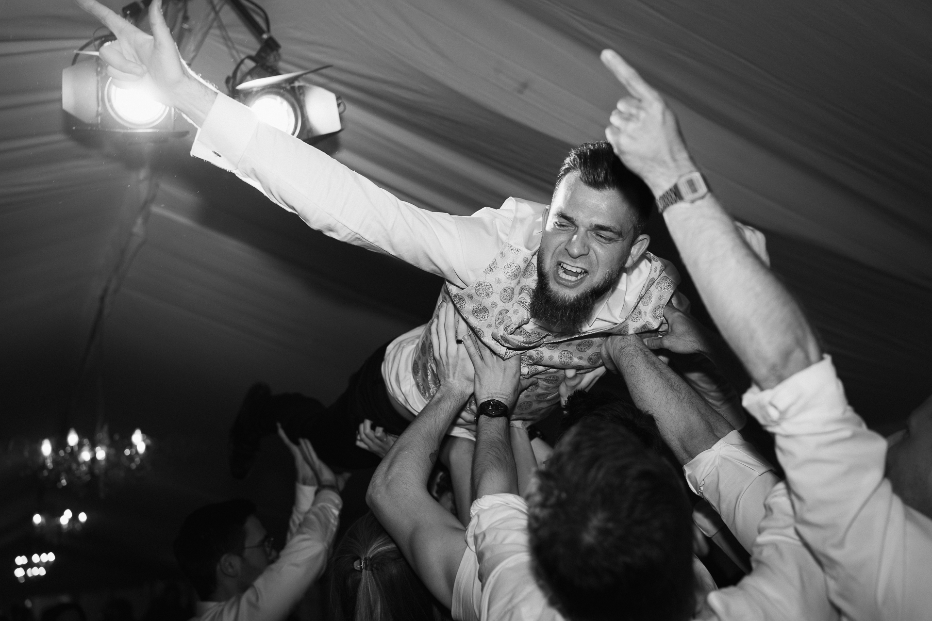 Bräutigam macht crowdsurfing auf den Händen seiner Gäste - emotionale, ausgelassene Hochzeitsfotografie